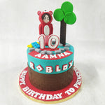 The inclusion of a Roblox tree and colourful bricks on this gamer theme cake adds an extra touch of whimsy and nostalgia and perched proudly atop is a Roblox male character donning a pink hoodie, embodying the iconic style and individuality celebrated in the gaming community.