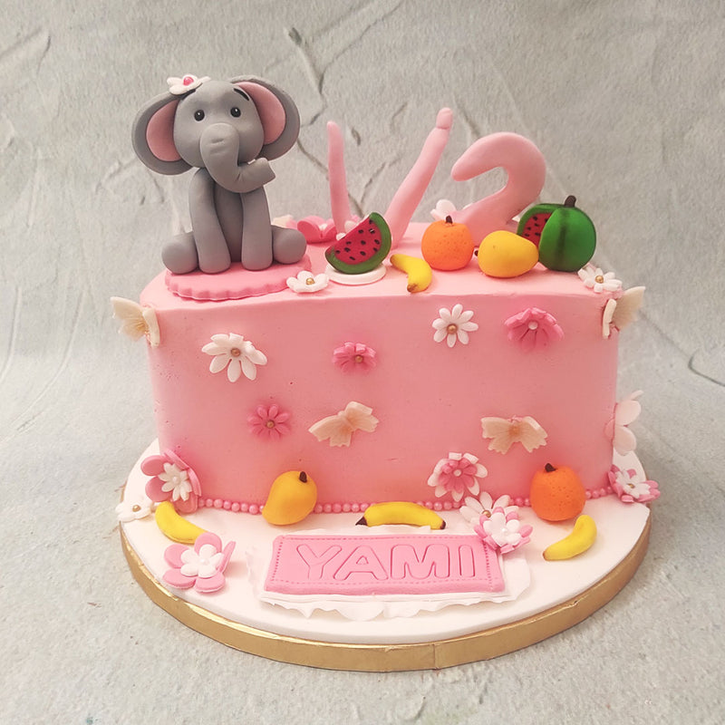  Adorned with edible figurines of flowers and fruits, this pink half birthday elephant cake is a true masterpiece that will captivate both young and old alike. 