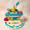 At the centre, a fondant baby in a bright yellow onesie sits atop this Six Months Nursery Theme Cake, holding a whimsical blue balloon, symbolising the innocence and wonder of this precious age. 