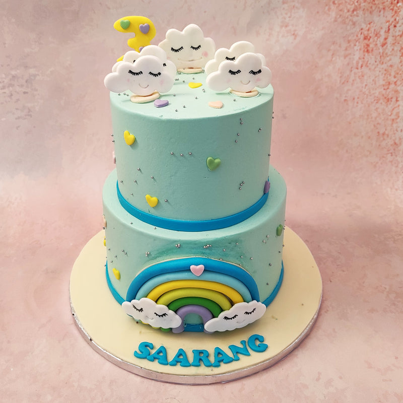 These smiley-faced clouds are thematically scattered throughout this two tier cloud cake, complemented by the silver pearls, vibrant colours of the rainbow and the matching colours hearts garnishing the entire design.