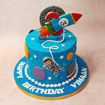 The astronaut on this galaxy themed cake is created in the likeness of an action figure and can be seen orbiting through the planets,  strung to a rocket figurine shooting out of the top with a realistic moon figurine behind it. 