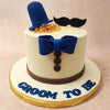 Perched atop the suit cake is a matching blue bowler hat, an iconic symbol of British culture and gentlemanly fashion. A black moustache playfully sits atop the gentleman cake, adding a touch of humour and whimsy.
