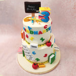 One side of this two tier classroom cake for teachers is a book with maths equations and on top of this school theme cake sits a miniature chalkboard, reminiscent of traditional teaching methods and fostering a sense of nostalgia.