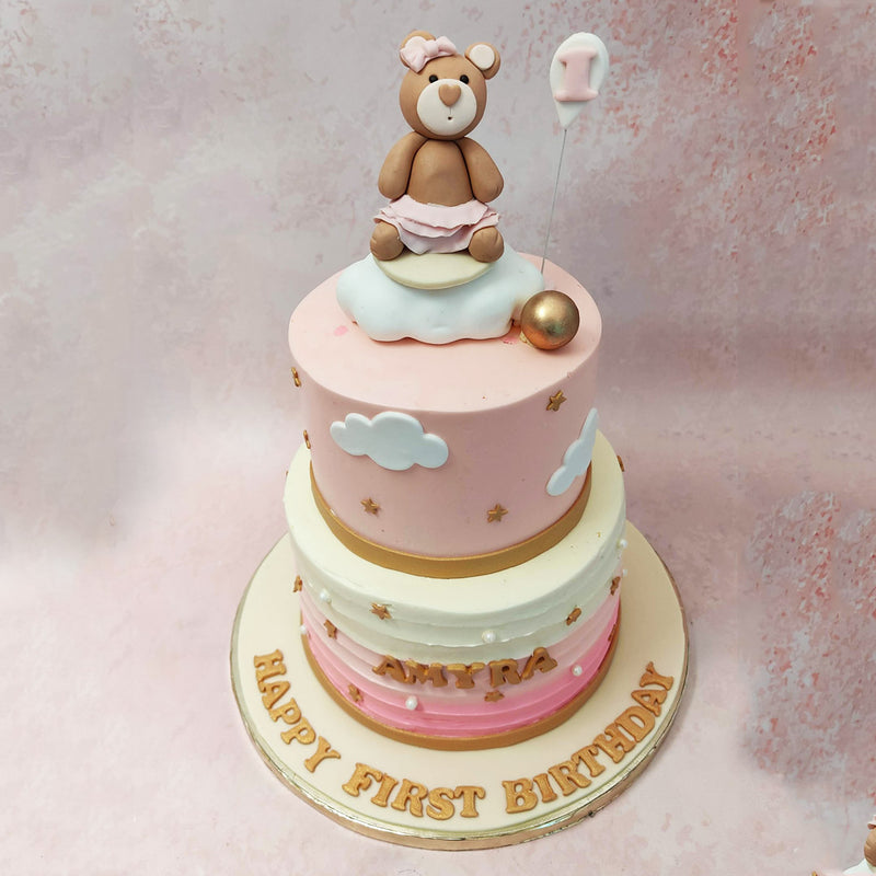 The top tier of this teddy bear cloud cake is adorned in a delicate baby pink and adds a touch of elegance to this playful creation. 