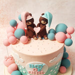 This Teddy Heart Cake is embellished with a delightful array of pastel blue and pink edible balls, adding a playful and festive touch. 