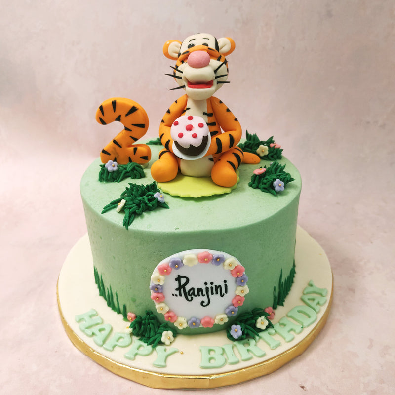 The base of this Tigger cake is adorned with a shade of grassy green, reminiscent of the Hundred Acre Wood where Tigger and his friends embark on their adventures. 