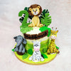 At the top of this Tropical Jungle Cake sits a golden lion with a wide-eyed, lovable expression, surrounded by monstera leaves, ready to roar in another year of fun. Down below, an adorable gathering of animal friends—including a shy elephant, playful zebra, and curious giraffe—bring the wild right to the party table.