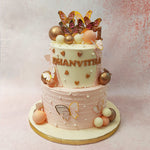 The pink, white and gold baubles potted all over further complement the delicate, feminine aesthetic of this two tier butterfly theme cake.