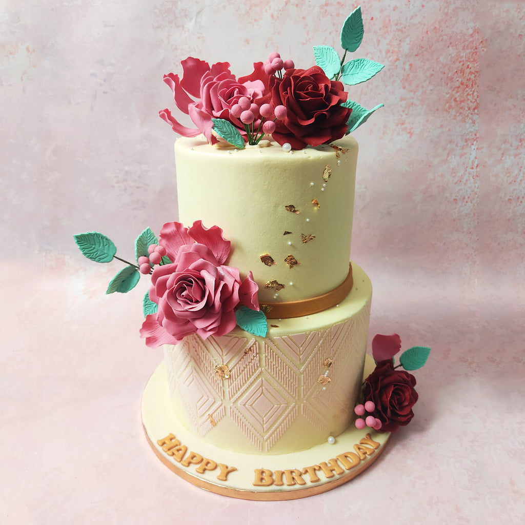 The bottom tier of this Two Tier Edible Flower Cake boasts delicate diamond-shaped patterns in a soft pink hue, adding a touch of subtle charm. 