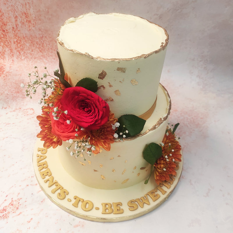 The smooth ivory fondant is gracefully embellished with golden flecks, adding a touch of luxury and opulence to this Two Tier Floral Cake. 