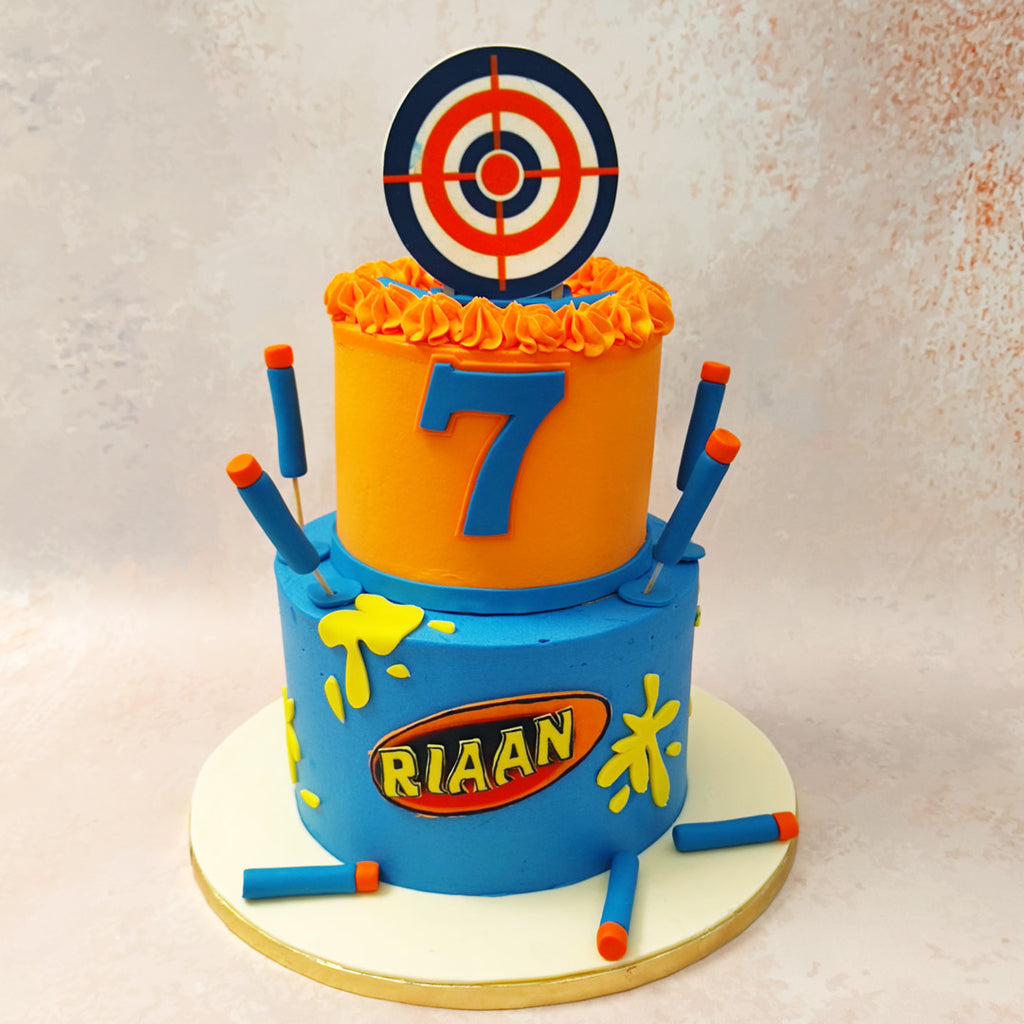 This Nerf target cake comes embellished with foam darts standing upright, shooting out of the base of the bottom tier, yellow paint splatters all around and a target board on top, all completely edible. 