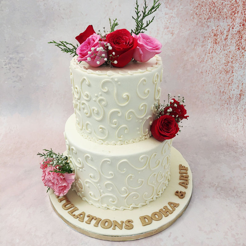 The fresh, bright pink and red roses embedded into this two tier rose engagement cake accent the all-white colour palette and add a touch of femininity to the design. 