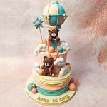 Perched atop the clouds on this Teddy Cloud Cake is an adorable teddy bear sporting a bow on her head, nestled in a hot air balloon. The balloon's strings are skillfully held by another teddy bear at the centre of the top tier.