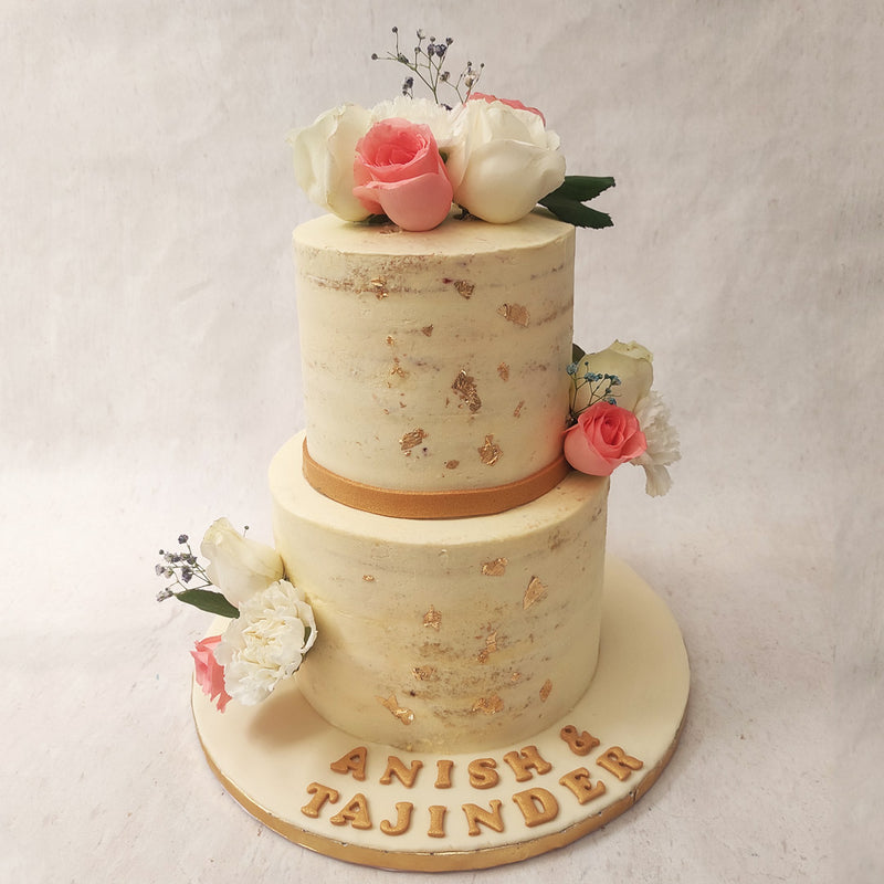 Both tiers of this anniversary cake come embellished in edible, gold leaves with a gold ribbon running through the centre.