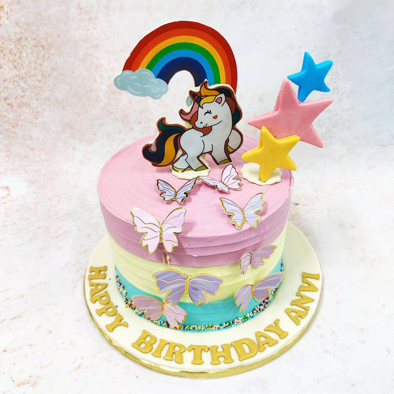 Surrounding the unicorn are an array of delicate butterflies and a vibrant rainbow, adding colour to this Unicorn and Butterfly Cake.