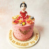  This Weaning Theme Cake features a meticulously crafted figurine of a baby girl in traditional attire, complete with a golden crown. 