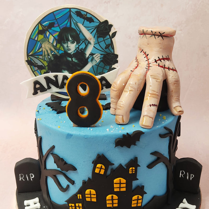 This Wednesday Addams cake also features a realistic figurine of Thing, everyone's favourite handy character who rests gracefully on top in all his gory glory. 