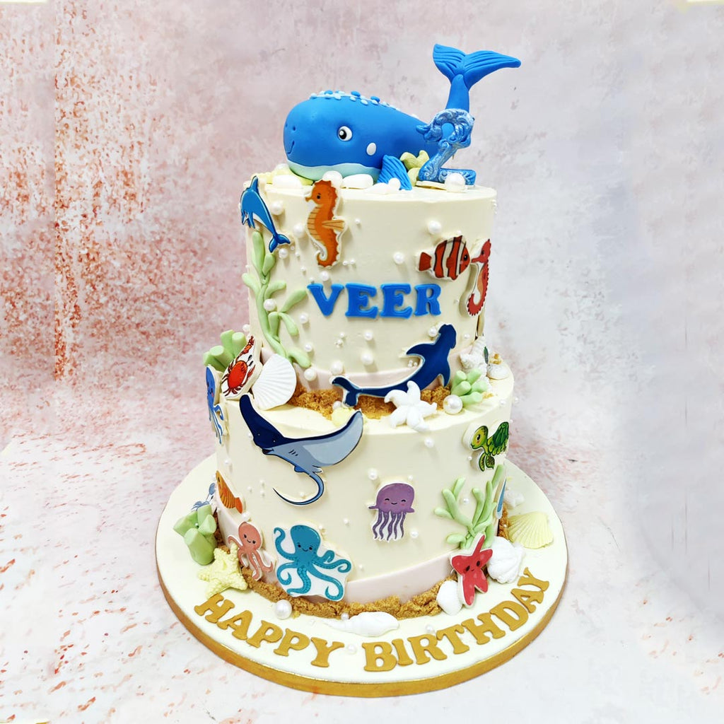 The artistic execution of this Whale Cake demonstrates exceptional attention to detail, from the hand-crafted sea creatures including charming seahorses, friendly sharks, and a smiling jellyfish, to the delicate pearl-like bubbles scattered across the surface. 