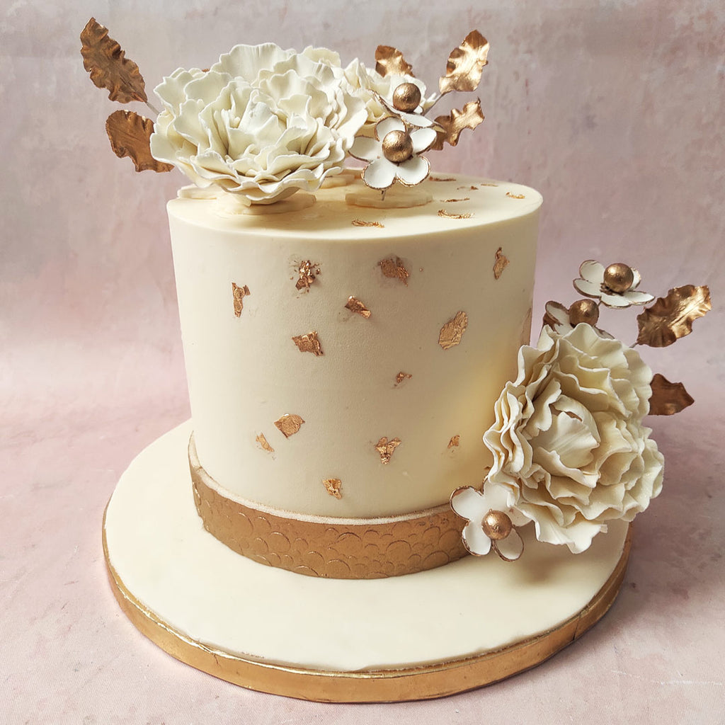 This White and Gold Floral Cake is a vision of sophistication, featuring a pristine white base adorned with golden accents, a symbol of opulent, everlasting unity.