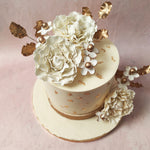 Edible gold leaves ornament this design like gilded dreams, transforming this White Cake With Flowers into a work of art. 