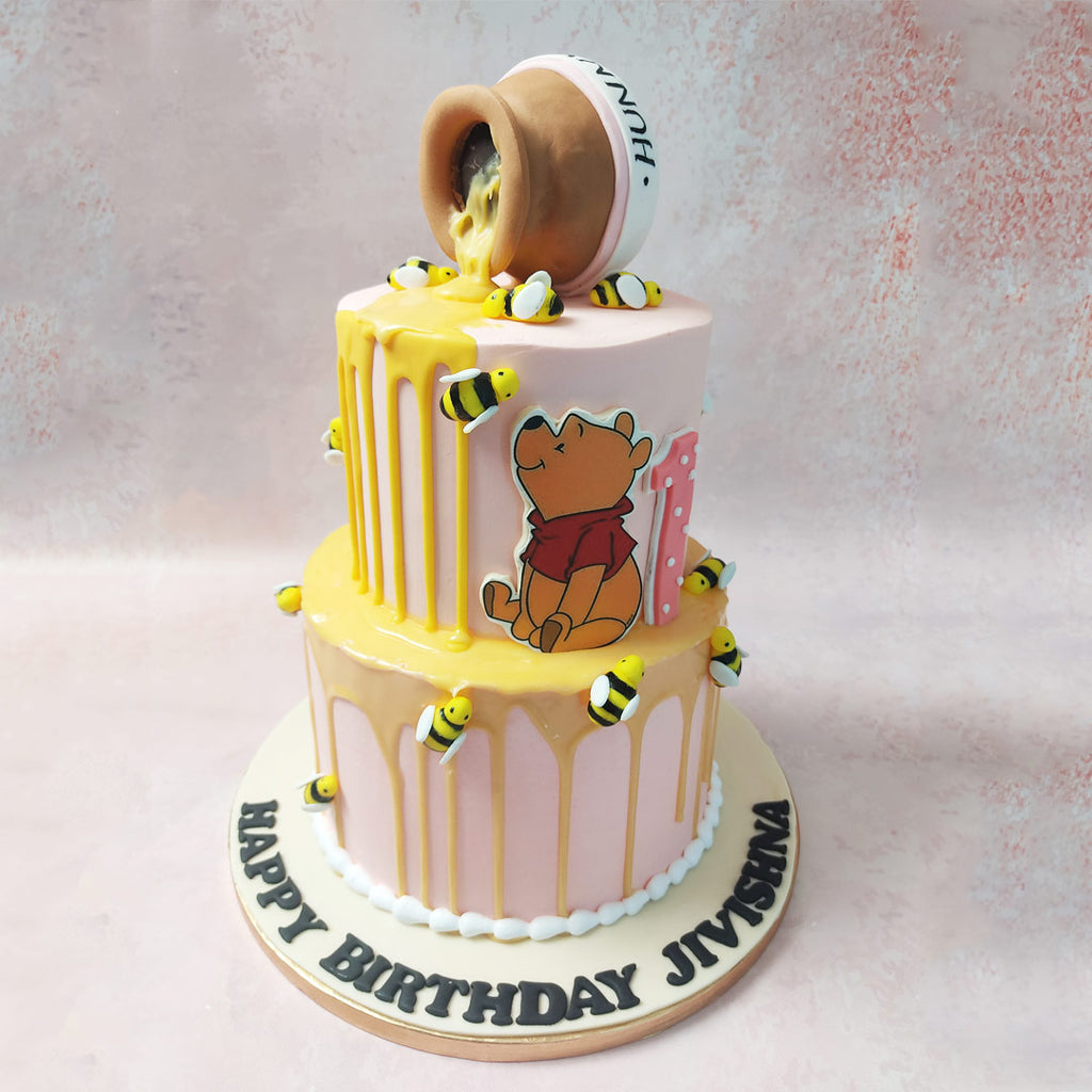 At the top tier of this Winnie The Pooh Honey Cake, behold a tumbled pot of honey cascading down the sides in a tantalising drip pattern.
