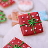 Close-up of a red square Christmas sugar cookie decorated like a green and white polka dot gift box.