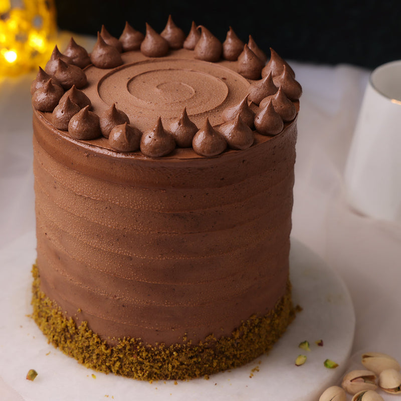 chocolate pistachio cake with base covered in chopped pistachios
