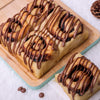 Freshly baked platter of Chocolate Sweet Rolls with chocolate ganache drizzle, served on a wooden board.