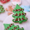 Close-up of a green Christmas tree sugar cookie decorated with red garland and white ornaments