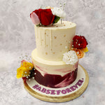 The base of both tiers comes in a classy off-white shade that is commonly seen on any wedding cake design but the bottom tier is coated with maroon smears like the strokes of a brush on an abstract painting.