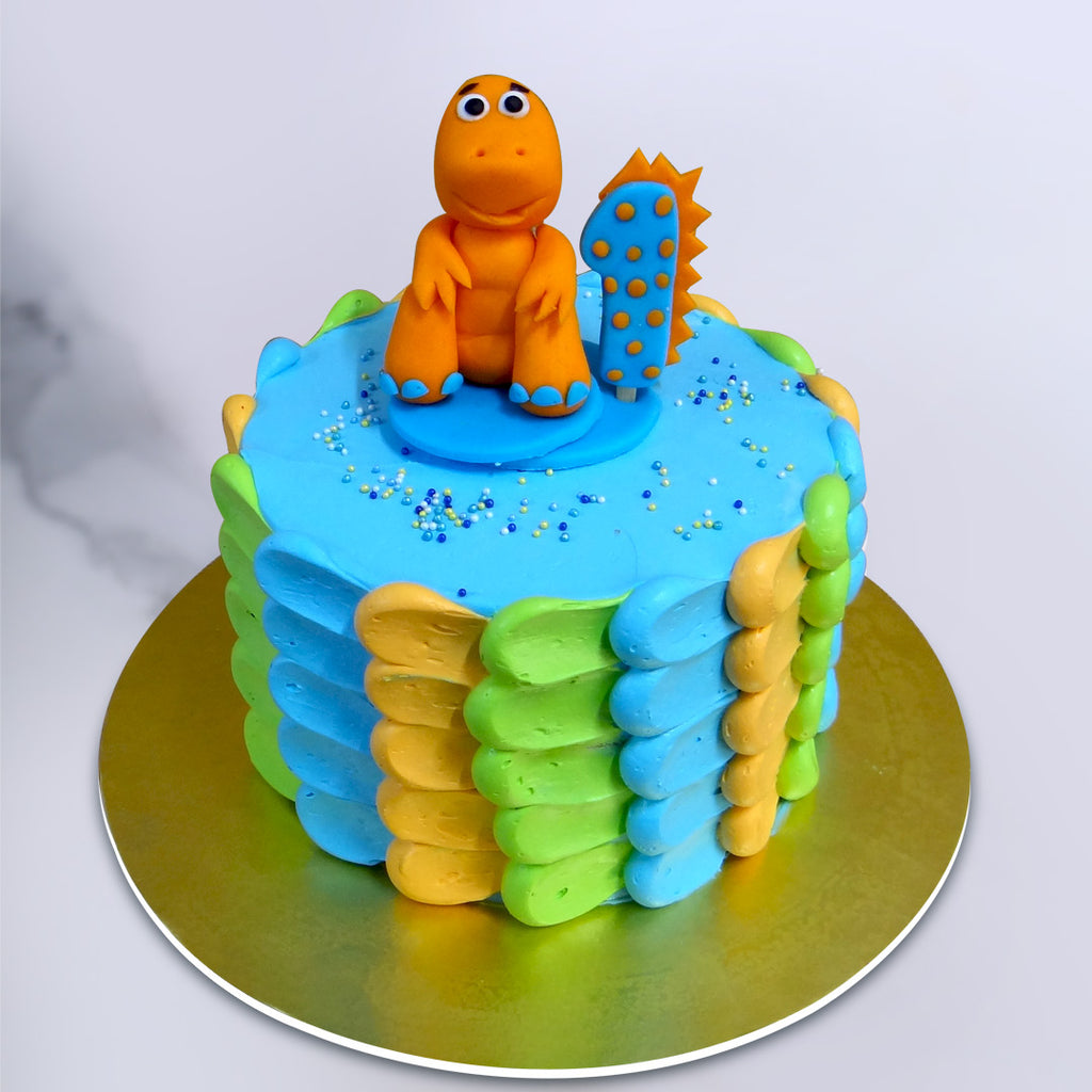 This baby dragon cake is cute and very adorable which holds a cute little baby dragon on top of the cake. The piping on this Dragon theme cake is actually a mixture of Blue, Green and orange colour which makes the cake stand out as a perfect kids birthday cake or a first birthday cake
