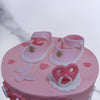 Top view of birthday cake for baby girl where you can see beautiful pink baby sandals with a pink pacifier and a beautiful butterfly sitting on top of this welcome baby girl cake