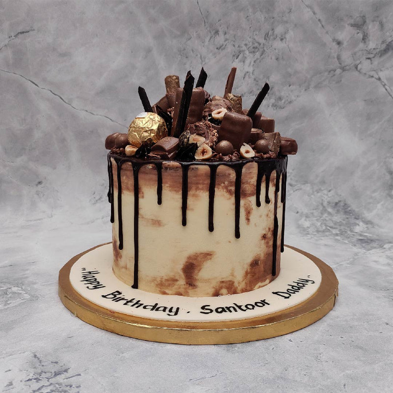 Front view of birthday cake for chocolate lover that is chocolate overloaded cake with different varities of chocolates on top and chocolate drips on sides to make it look more tasty and yummy