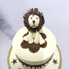 A doll-like lion made entirely edible, stands guard over this kids birthday cake and the colour theme of this cartoon cake is brown and pale yellow like the colours one would see on a jungle safari and a brown banner is centrally placed, displaying the name of the birthday boy/girl