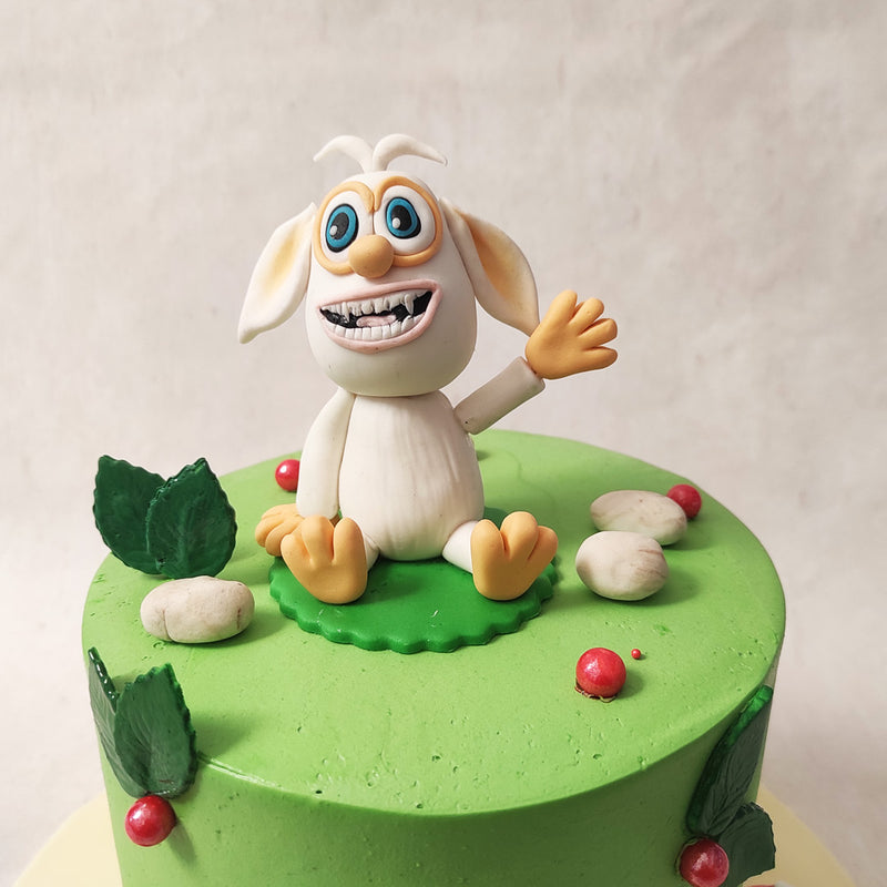 A figurine of Booba sits on top of this cartoon cake design, waving hi and smiling adding to the charm of this realistic figurine