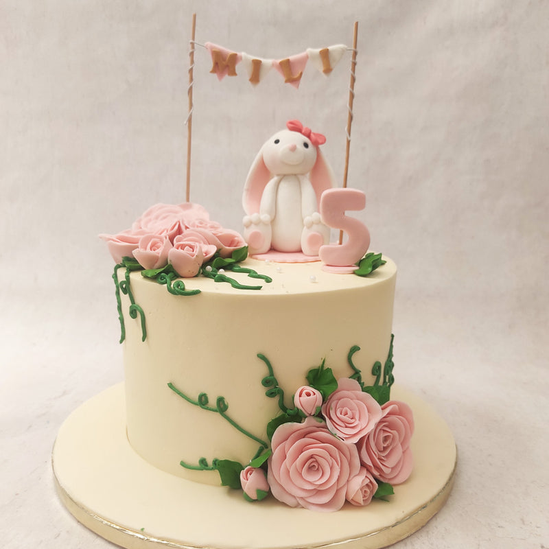 With a clean, white base this bunny theme cake sports a bouquet of pink, hand-painted buttercream flowers at the top and the bottom.