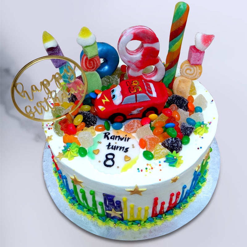 On top of this cartoon cake, sits a variety of candy from lollipop sticks to jujips to a candy version of the number of years your little one reached this year