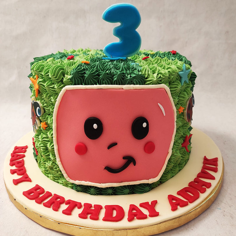 This Cocomelon theme birthday cake for kids is shaped and created like a watermelon but one that is garnished with buttercream piping and features the happy face often associated with the show.