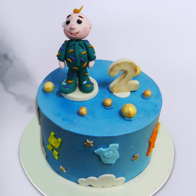 Ideal as a kids birthday cake or more specifically, a 2nd birthday cake for boys, this JJ birthday cake has the cartoon character Baby JJ standing proudly in his adorable green onesie next to the bold number 2 on top of a sky blue base decorated with clouds, stars and colourful baby clothes. 