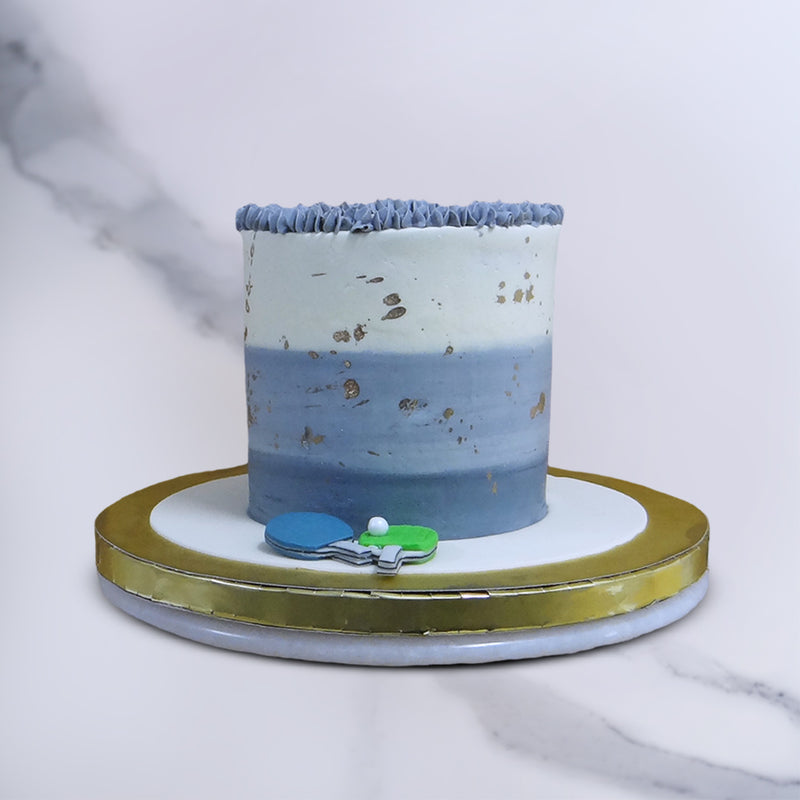 A marble-like gradient is used for the tall base of this birthday cake for computer programmers in blue to white. A beautiful blue and textured buttercream borders the top of this coding cake and small gold leafs embellish it all over