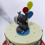 The smooth yellow base of this cute elephant cake is decorated with bunt flag banners like those you would see at a carnival or any other festival. 