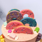 Top view of donut theme birthday cake with 5 donut shaped cookies with royal icing layer on top. This candy theme cake is the best birthday cake for your little one as a kids birthday cake
