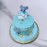 Top view of elephant themed 1st birthday cake shows us a happy and smiling face of baby elephant on top while sitting on a airplane surrounded by clouds and stars