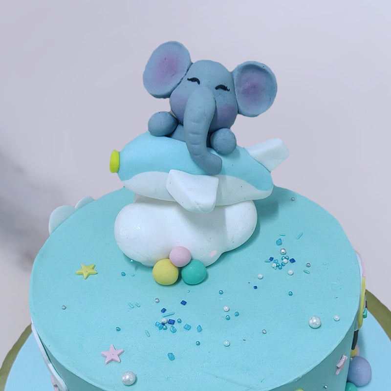 Flying elephant birthday cake for a kids 1st birthday where a baby elephant is sitting smiling on top of a plane and having his tour of imagination. This cute elephant themed birthday cake will surely be loved by any kid