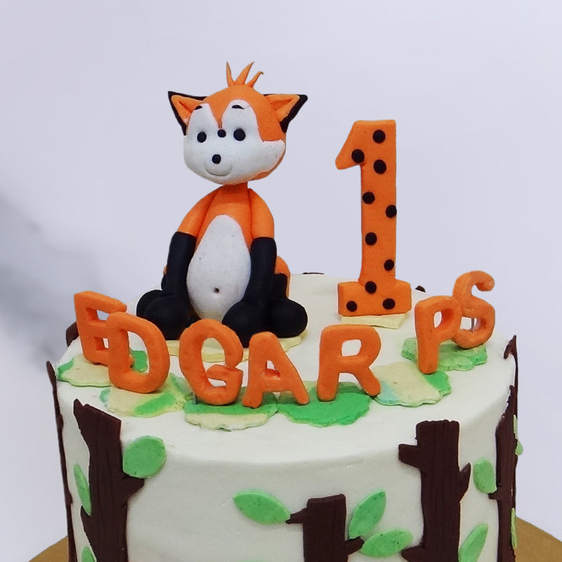Zoom view of cute fox cake where a baby fox is sitting on top of the cake and smiling at you. This is the best 1st birthday cake for a baby