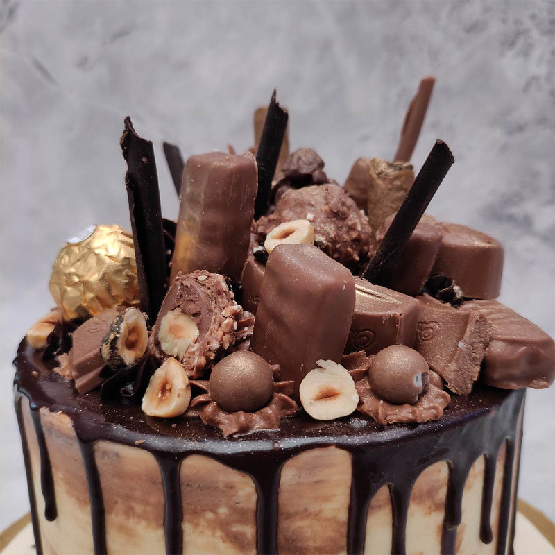 Zoomed view of full chocolate cake where you can see different varieties of chocolates like 5stars, Dairy-milk silk, Rochers and many more. This chocolate overloaded cake is perfect for a chocolate lover