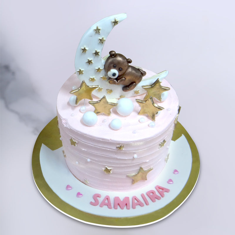 Top view of this Hug the moon cake where the pink cake for her holds a crescent moon and golden stars surrounding the moon. This is surely a best option for a baby shower cake or as a kids first birthday cake