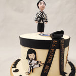 A two-dimensional figurine of a boy and girl adorned in their Gi or Karate clothes can be spotted on both sides of the circumference of this birthday cake for kids. They are in combat or Kumite position, ready to battle. 