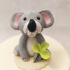  The showstopper is this animal theme cake topper i.e. the near life-sized figurine of the Koala sitting on top holding one of these buttercream leaves in its paw.