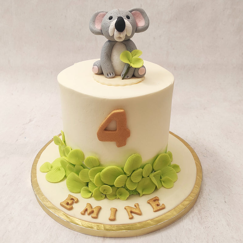  This Koala birthday cake for kids features a simple white base with light green leaves embellishing the bottom made out of velvety buttercream.